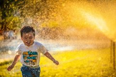 boy playing in sprinklers